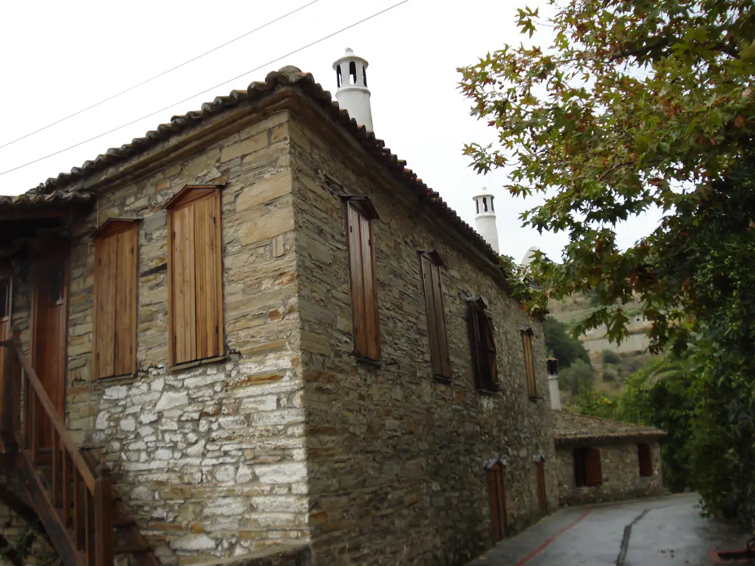 A traditional stone house with wooden shutters on a cobbled lane in the old village of Nikiti