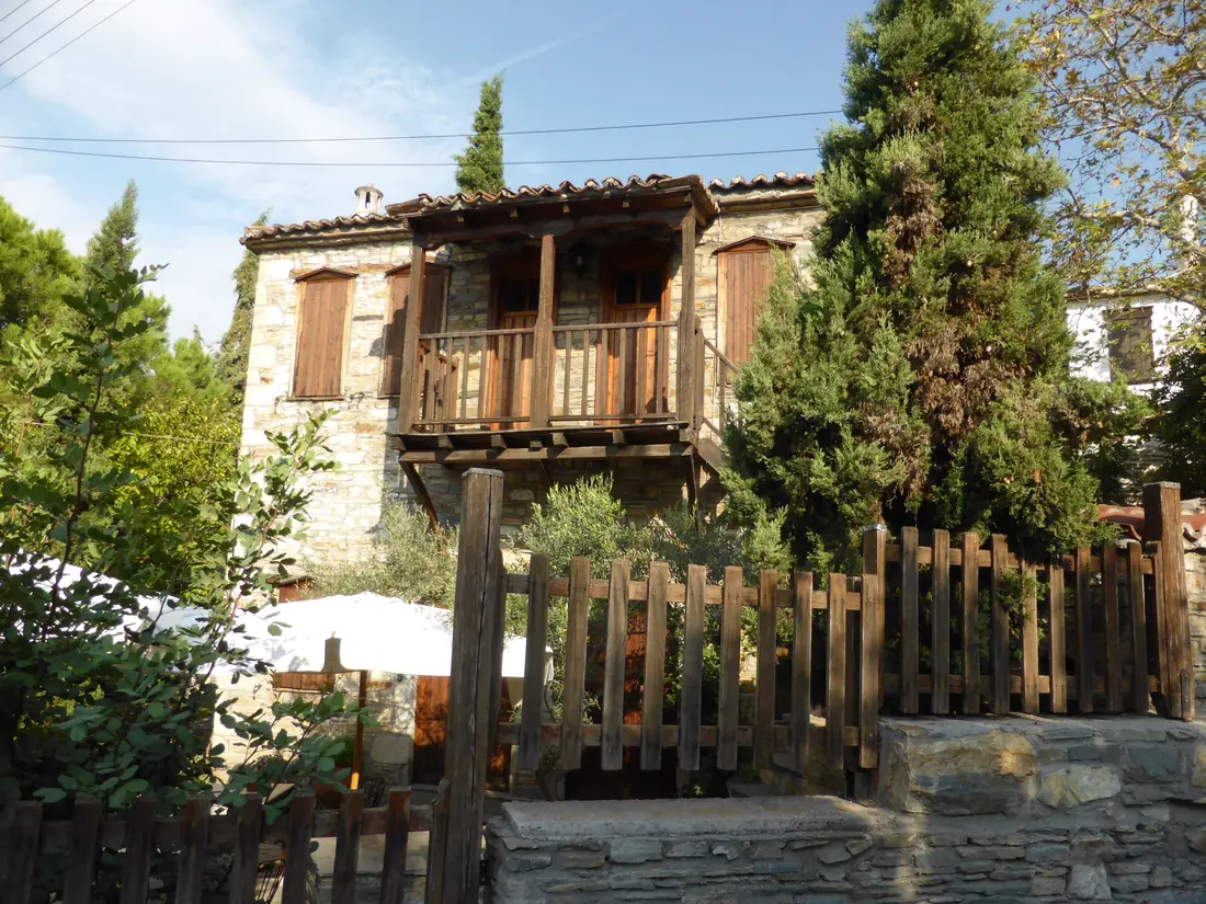 A traditional stone house with a wooden balcony in the old village of Nikiti