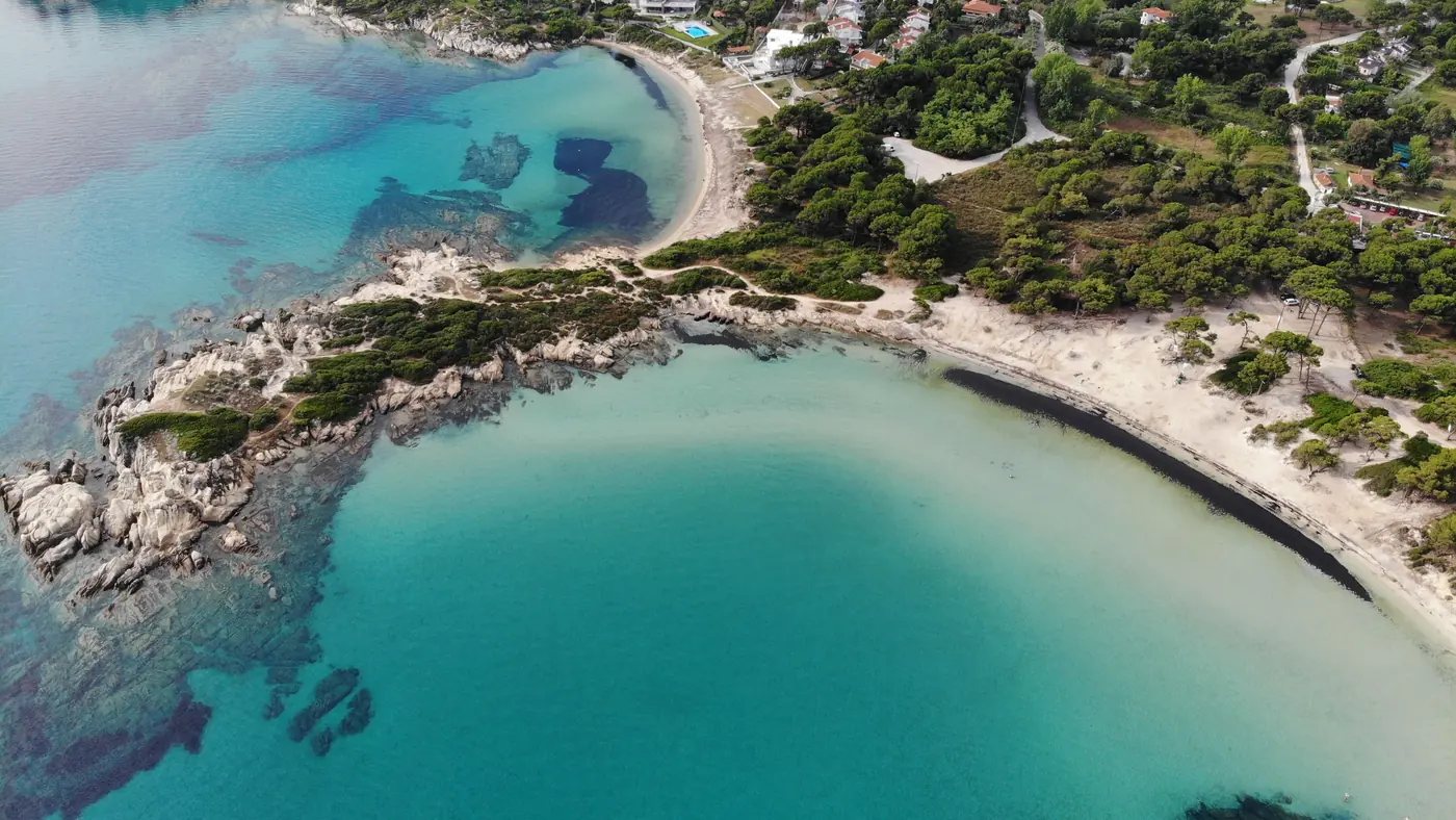 Sithonia's west coast from the air, the road following the coastline across wooded slopes